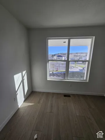 Wood-finish flooring, white baseboards, and a large window providing ample natural light