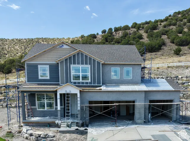 Two-story construction featuring a shingled roof, partial siding, and multiple window installations