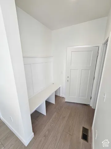 Built-in bench seating with wainscoting, wood-finish flooring, and a three-panel door