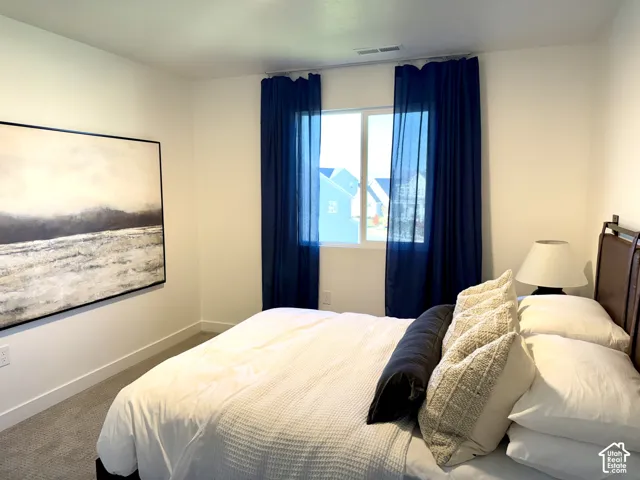 Recessed window with dark drapes, light-toned walls, and carpet flooring