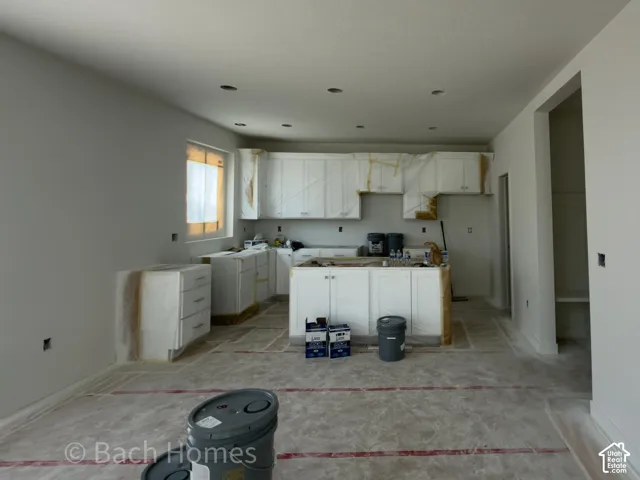 Kitchen with white cabinetry, a central island, recessed lighting, and a window