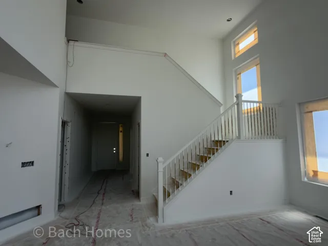 Two-story foyer with a staircase featuring painted white balusters and a newel post, recessed lighting, and tall windows