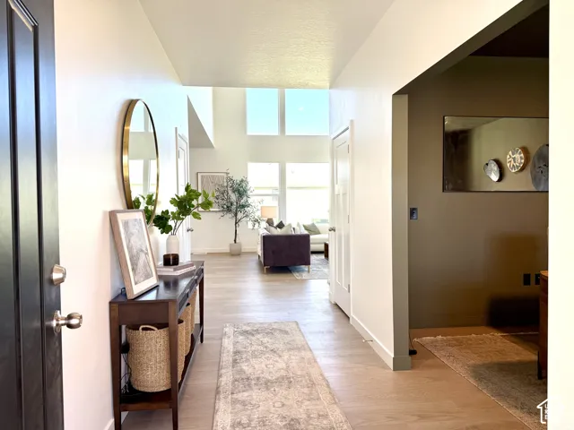 High ceilings with clerestory windows, wood-finish flooring, recessed lighting, and a dark wood console table