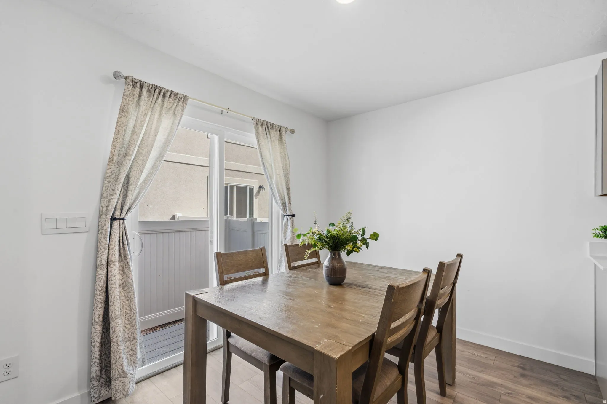 White walls, wood-finish flooring, recessed lighting, and a sliding glass door with a transom window