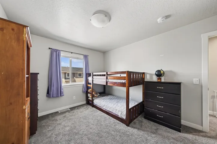 Light gray wall paint, textured ceiling, flush mount ceiling light, window with white trim, and gray carpet