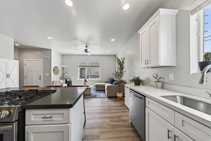 Kitchen featuring stainless steel appliances, a gas range with a dark countertop, white shaker cabinetry, and wood-finish flooring