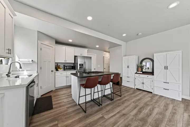 Kitchen featuring a center island with a gas cooktop, white cabinetry, stainless steel appliances, wood-finish flooring, and recessed lighting