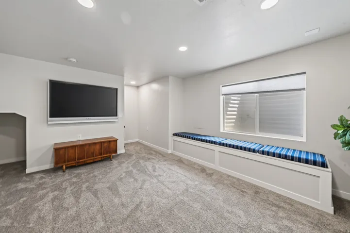 Spacious room featuring recessed lighting, a built-in window bench, a large window, and light grey carpet
