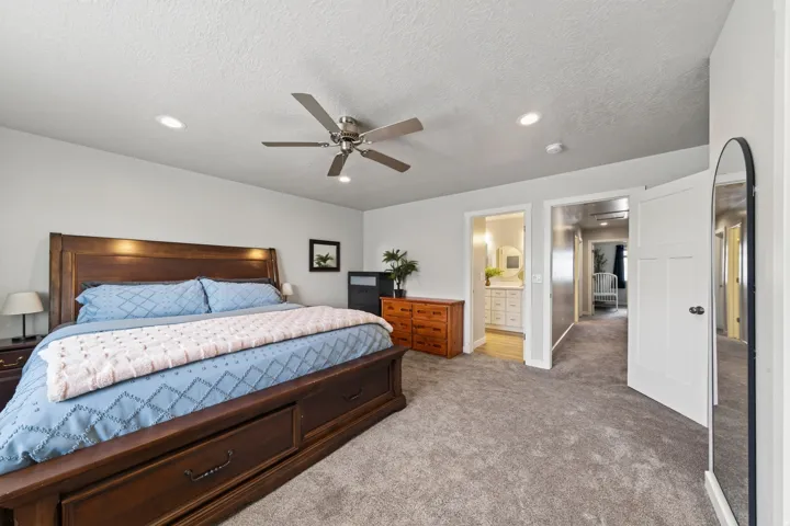Recessed lighting, ceiling fan, plush carpet flooring, white paneled doors, and wood-finish bedroom furniture