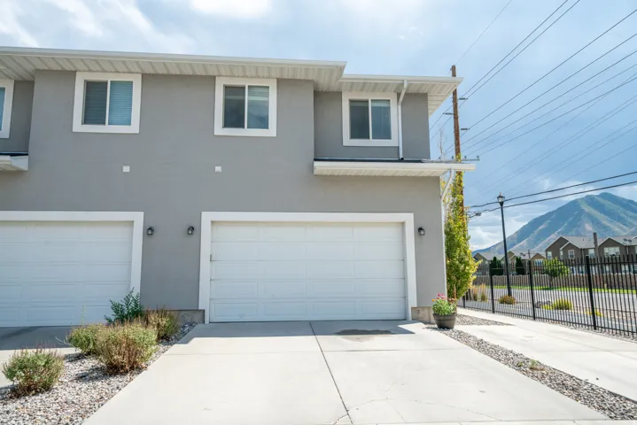 Stucco exterior with white-framed windows, multiple garage bays, and paved driveways
