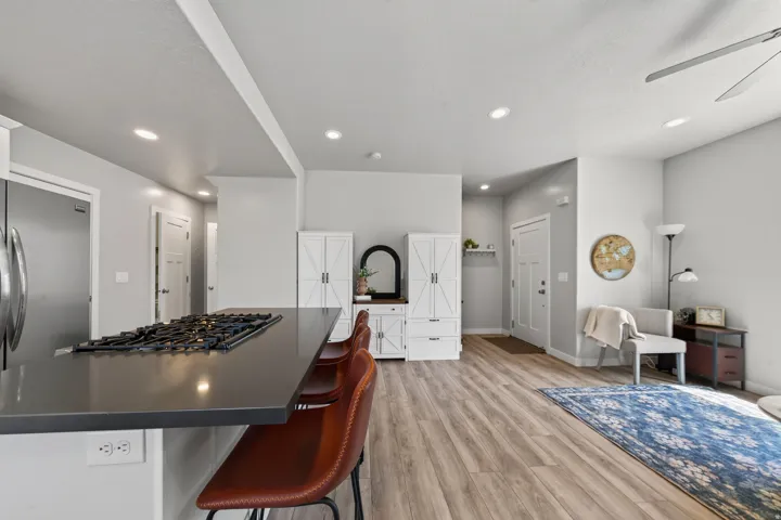 Wood-finish flooring throughout, recessed lighting, ceiling fan, built-in cabinetry, and a dark stone countertop with an integrated cooktop