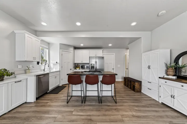 Modern kitchen featuring white cabinetry, stainless steel appliances, wood-finish flooring, recessed lighting, and a center island with a cooktop