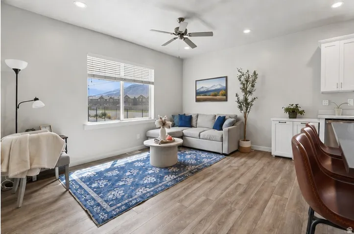 Recessed lighting, wood-finish flooring, ceiling fan, large window with blinds, and white built-in cabinetry