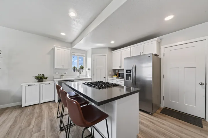 Kitchen featuring white cabinetry, stainless steel appliances, a center island with a cooktop, wood-finish flooring, and recessed lighting