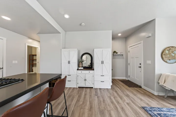 Wood-finish flooring throughout, recessed lighting, white built-in cabinetry, and a modern entry door