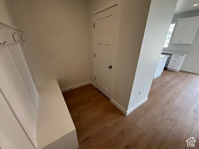 Built-in bench with coat hooks, wood-finish flooring, and white paneled doors