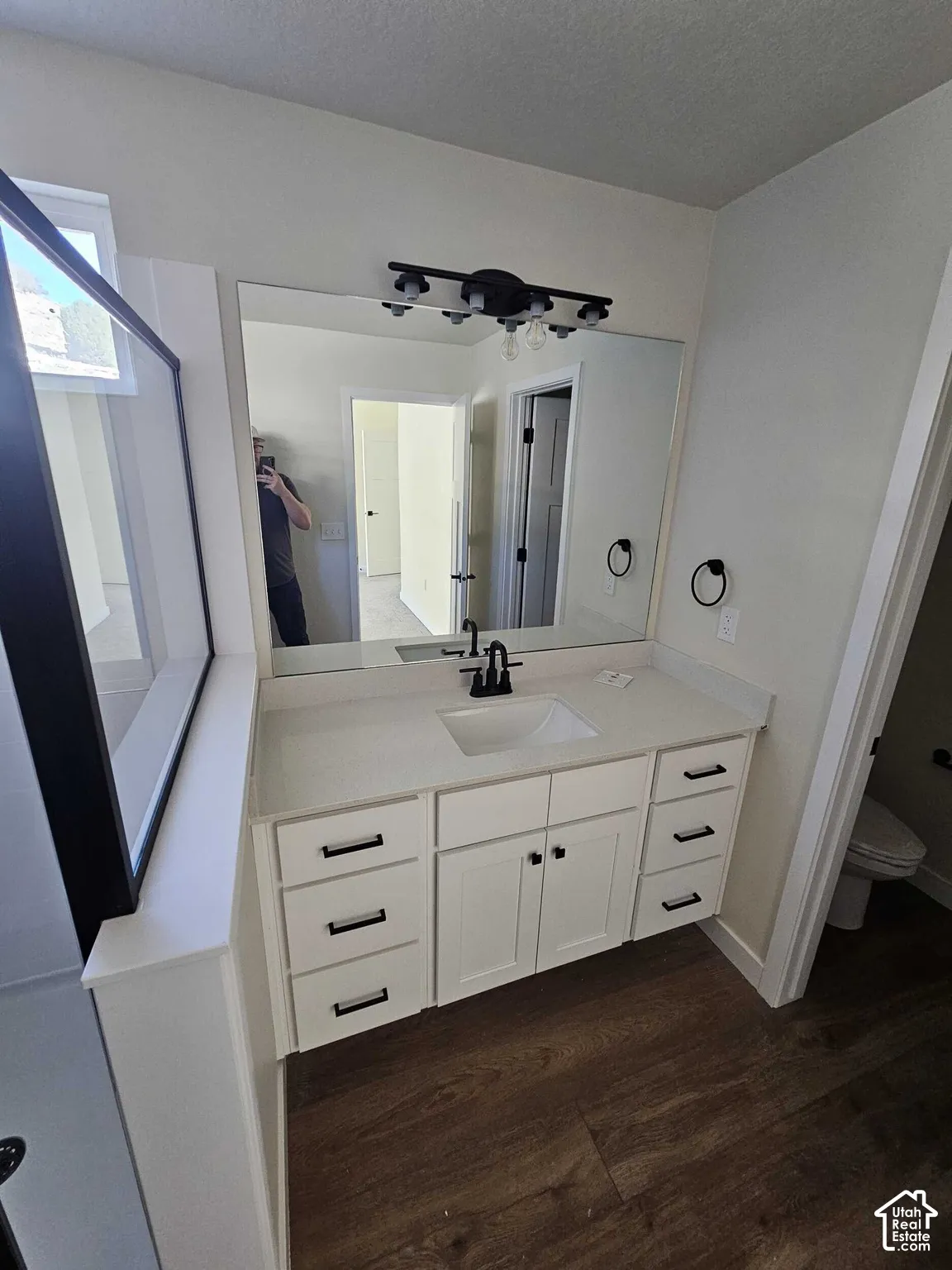 White vanity with a light-toned countertop, undermount sink, and matte black faucet