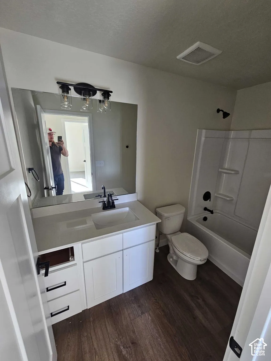 Vanity with integrated rectangular sink, white cabinetry, and dark wood-finish flooring