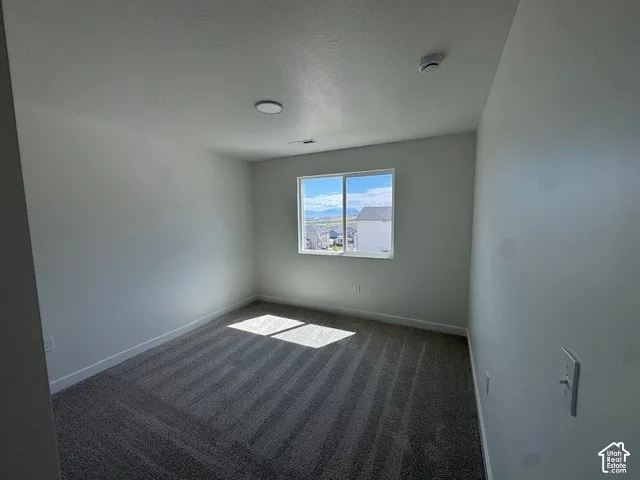 Neutral wall finishes, recessed lighting, and a single window with white trim, all complemented by striped carpeting