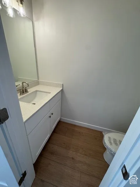 White vanity with integrated sink, light-colored countertop, and wood-finish flooring