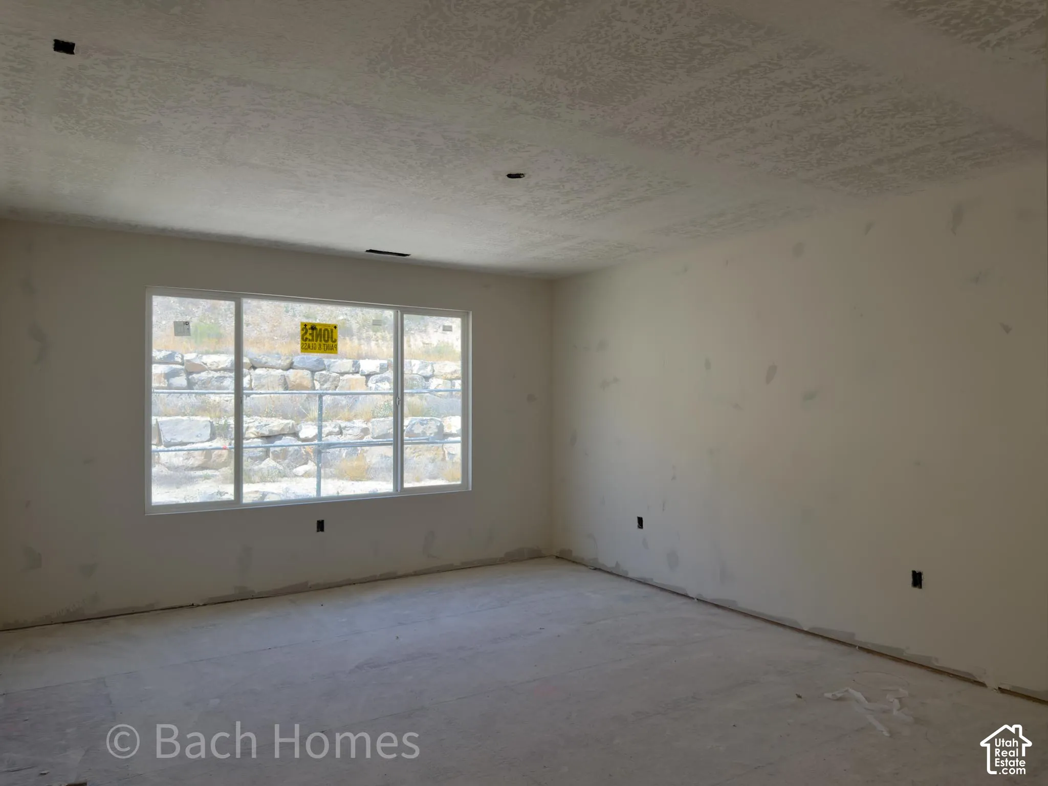 Expansive room with neutral wall tones, textured ceiling, and a large multi-pane window