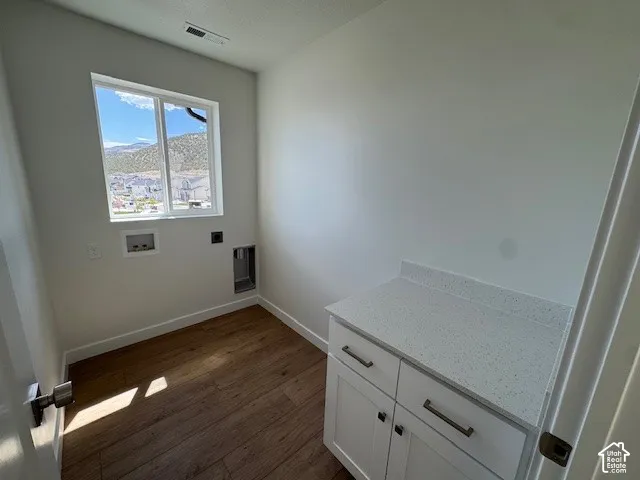 Wood-finish flooring, white cabinetry, integrated countertop, and a window providing natural illumination