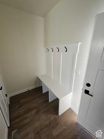 Built-in bench with integrated wall paneling, black coat hooks, and wood-finish flooring