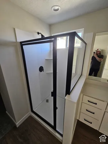 Walk-in shower with black-framed glass enclosure, matte black fixtures, and integrated shelving