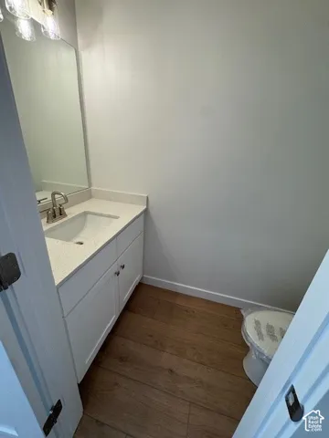 White vanity with integrated sink, light-colored countertop, and wood-finish flooring