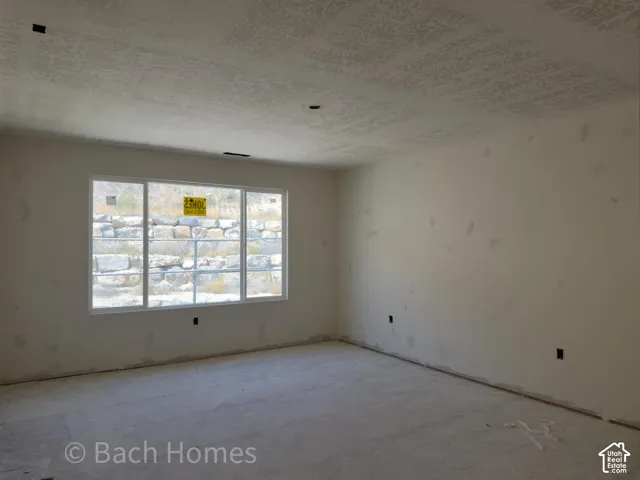 Expansive room with neutral wall tones, textured ceiling, and a large multi-pane window