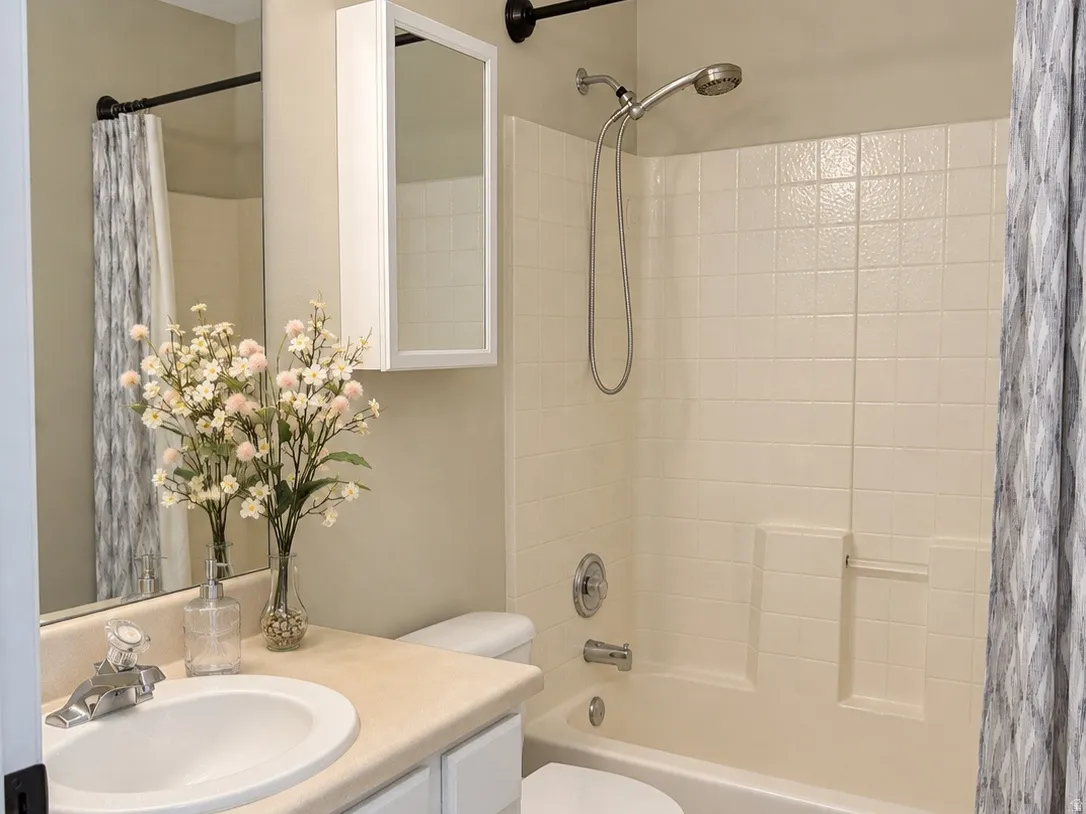 White vanity with an integrated sink, cream countertop, and a medicine cabinet with a mirrored door