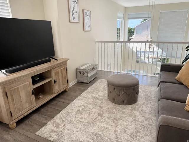 Upper-level living space featuring wood-finish flooring, a white spindle railing, and multiple windows