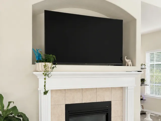 Integrated fireplace with a tiled surround, a white mantel, an arched alcove, and wood-finish flooring