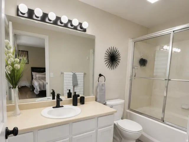White shaker-style vanity with a light-toned countertop, oval undermount sink, and matte black faucet