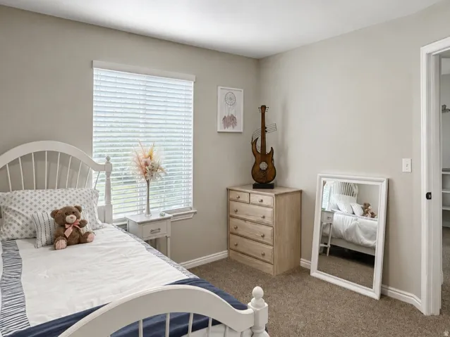 Neutral wall paint and natural light, featuring a window with blinds, recessed ceiling lighting, and carpet flooring