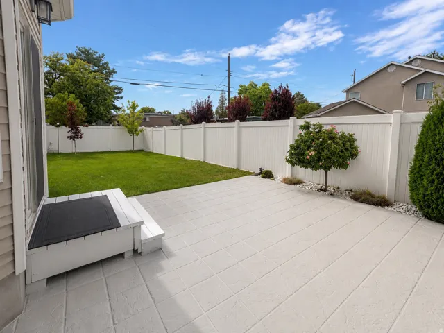 Expansive stamped concrete patio with direct access to a private fenced yard and manicured lawn
