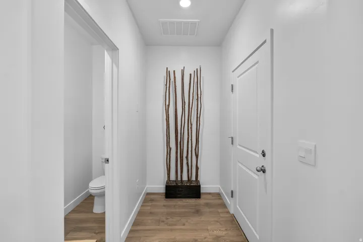 Wood-finish flooring throughout, white walls, recessed lighting, and a white interior door with paneling