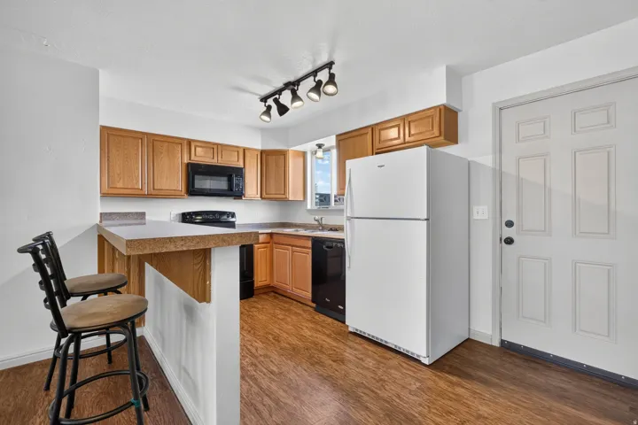 Kitchen featuring wood-finish flooring, oak-finish cabinetry, track lighting, and a built-in microwave