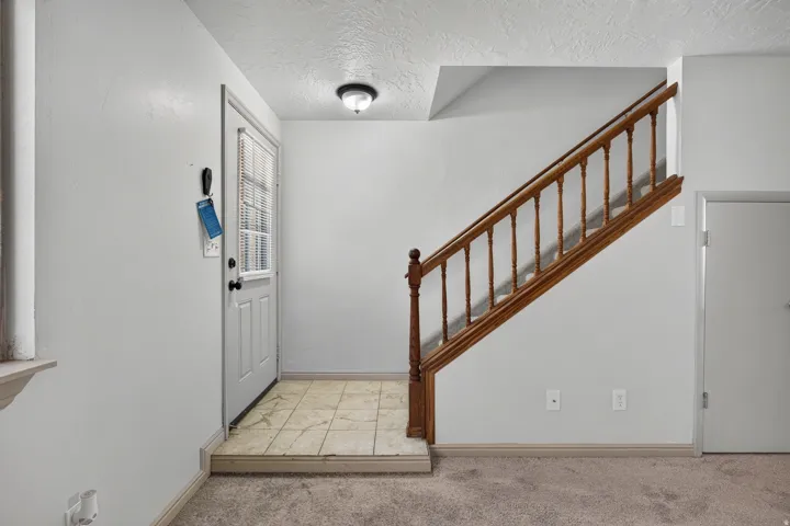 Entryway featuring ceramic tile flooring, a paneled door with window lites, and a built-in staircase with wood railing