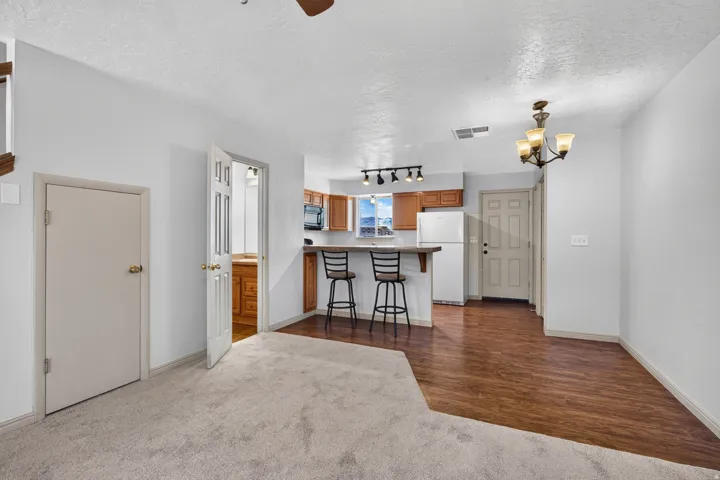 Open-concept living area with mixed flooring, featuring carpet and wood-finish flooring