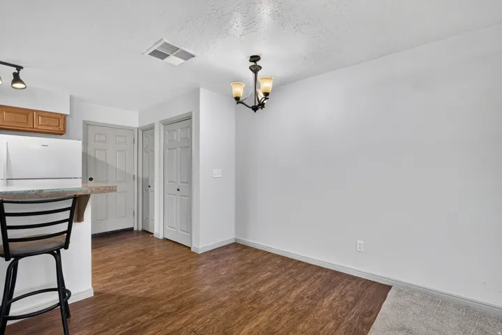 Wood-finish flooring, white walls, overhead track lighting, built-in cabinetry, and a ceiling-mounted chandelier