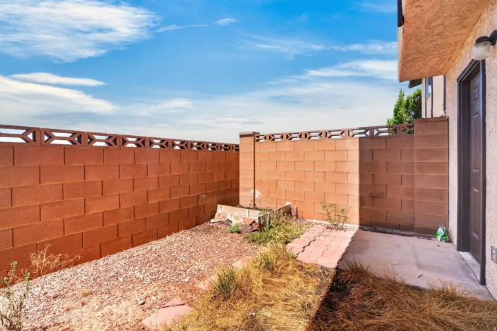 Enclosed exterior space featuring block walls with decorative accents, an exterior door, and an exterior wall light fixture