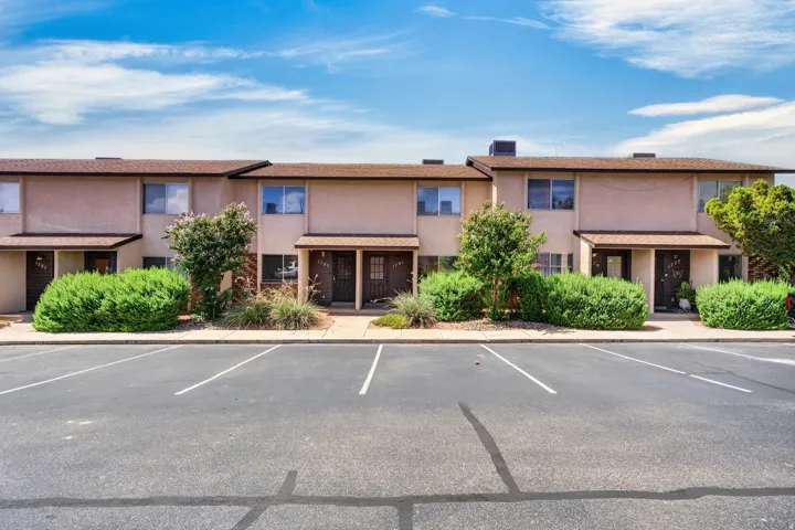 Multi-unit building featuring stucco exterior, individual entryways, and mature landscaping