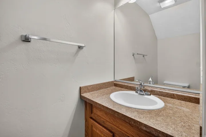 Vanity with an integrated sink, polished chrome faucet, and expansive wall-mounted mirror