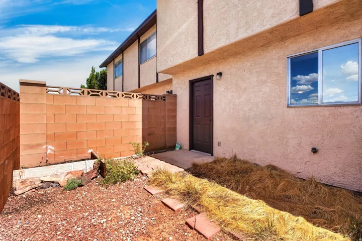 Stucco exterior with a brown entry door, a window with aluminum framing, and an exterior wall-mounted light fixture