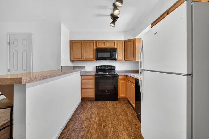 Kitchen featuring wood-finish flooring, wood cabinetry, built-in microwave, and track lighting