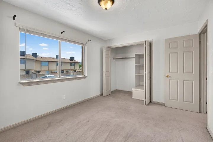Wall-to-wall carpeting, window with blinds, and a built-in closet with shelving