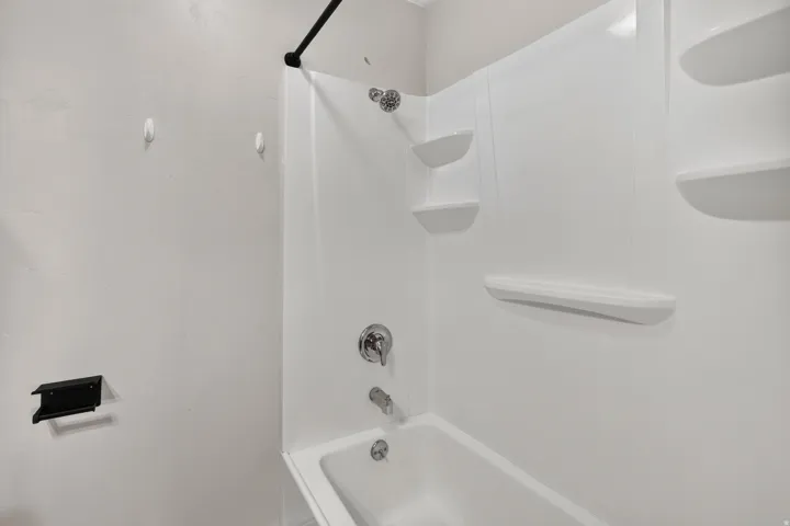White bathtub and shower surround with integrated shelving