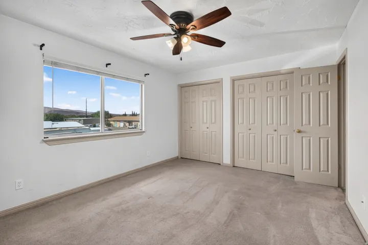 Expansive window with a wide sill, dual bi-fold panel doors, and a ceiling fan with integrated lighting