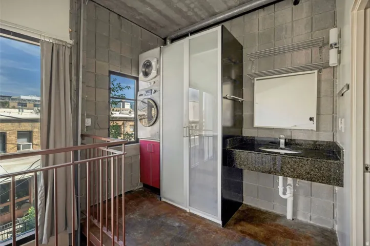 Exposed concrete block walls with an integrated vanity featuring a dark countertop and undermount sink
